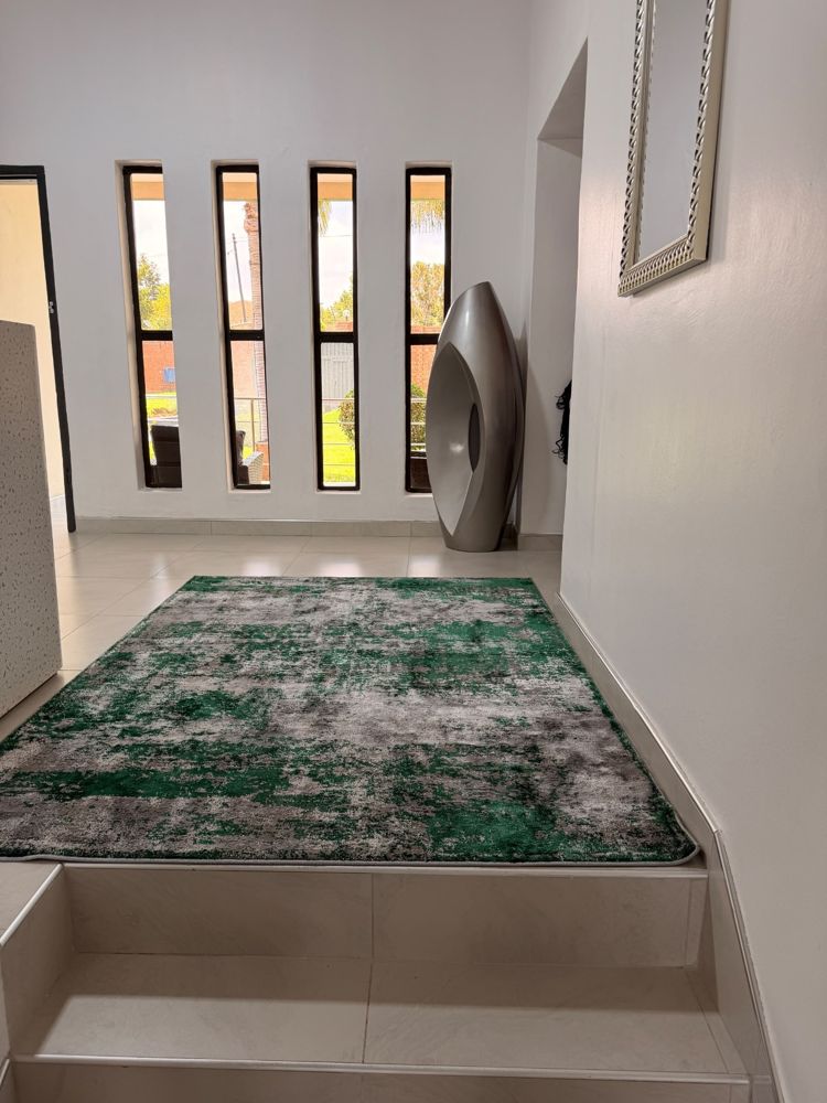 Bright entrance hall with tall narrow windows and a green rug