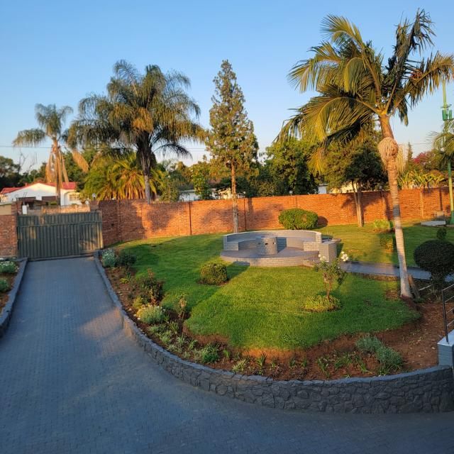 Palon's garden with palm trees, lawn and a round fire-pit seating area at golden hour