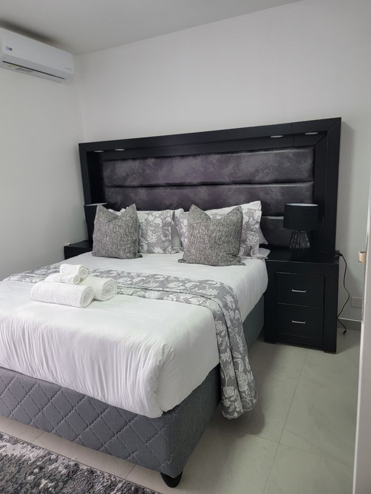Queen-sized bed with upholstered headboard, bedside lamps and air conditioning